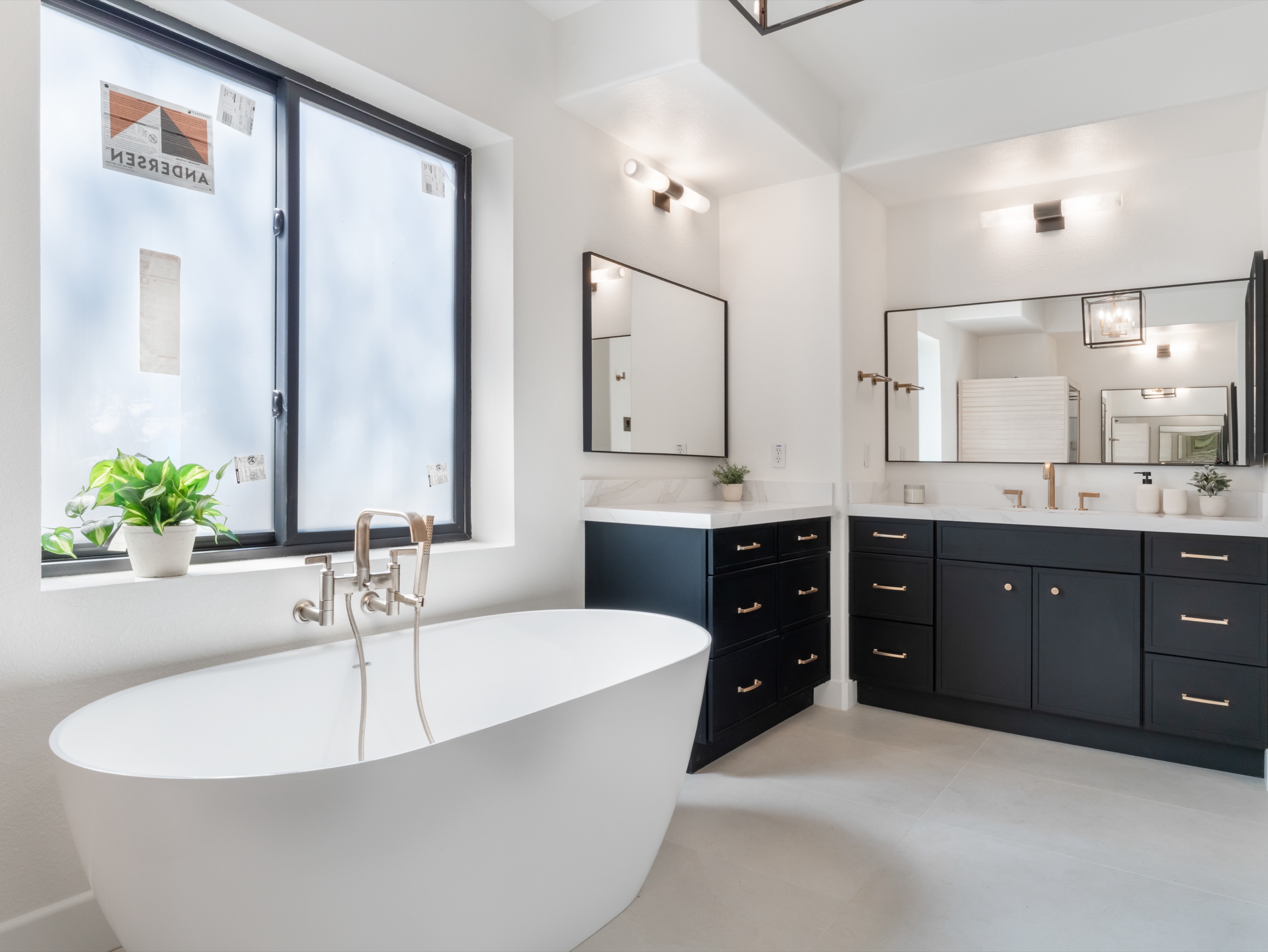 Primary bath with freestanding tub, navy double vanities and brass fixtures