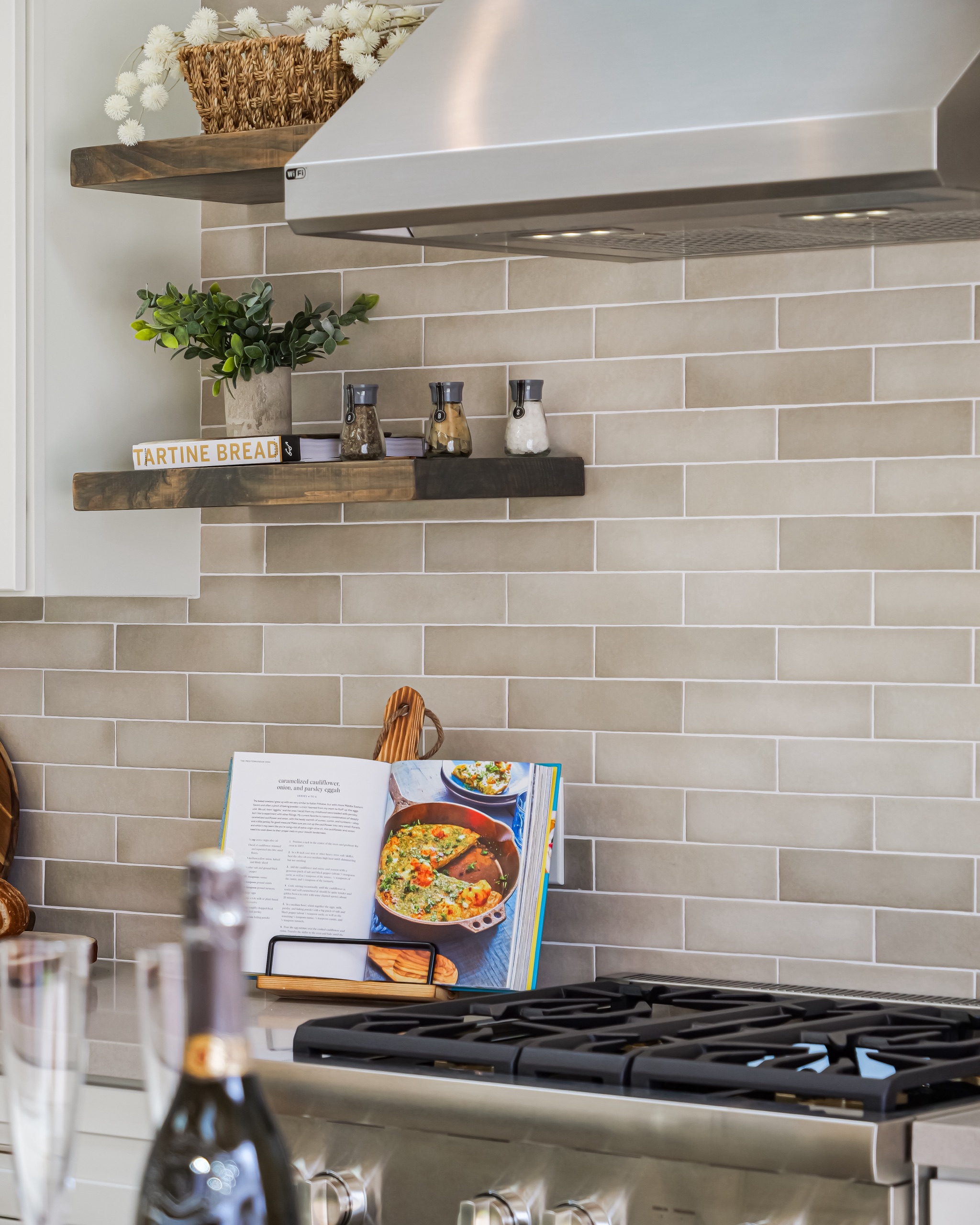 Warm-wood floating shelves and a range beneath a rattan pendant