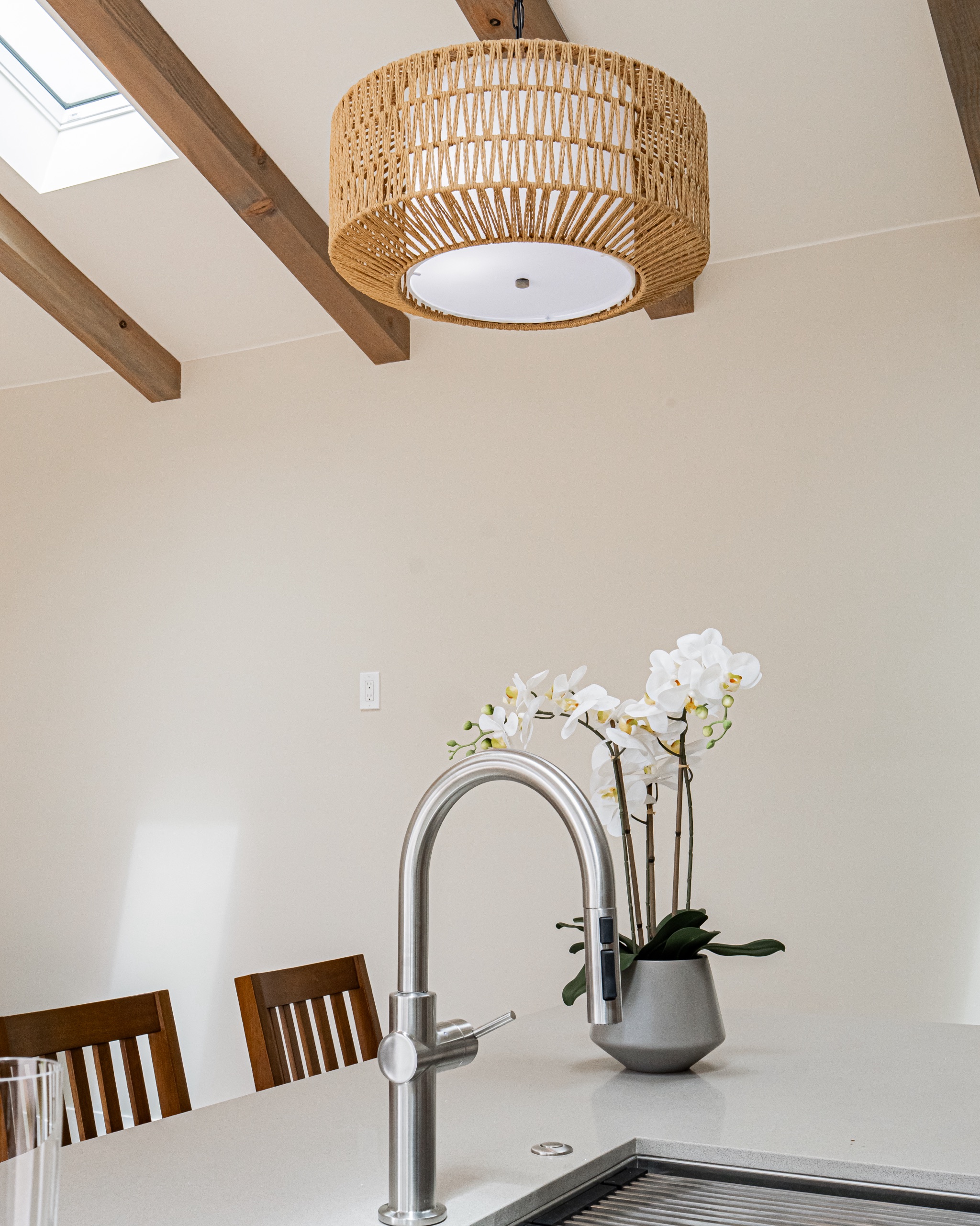 Woven rattan pendant beneath the vaulted, beamed ceiling and a skylight