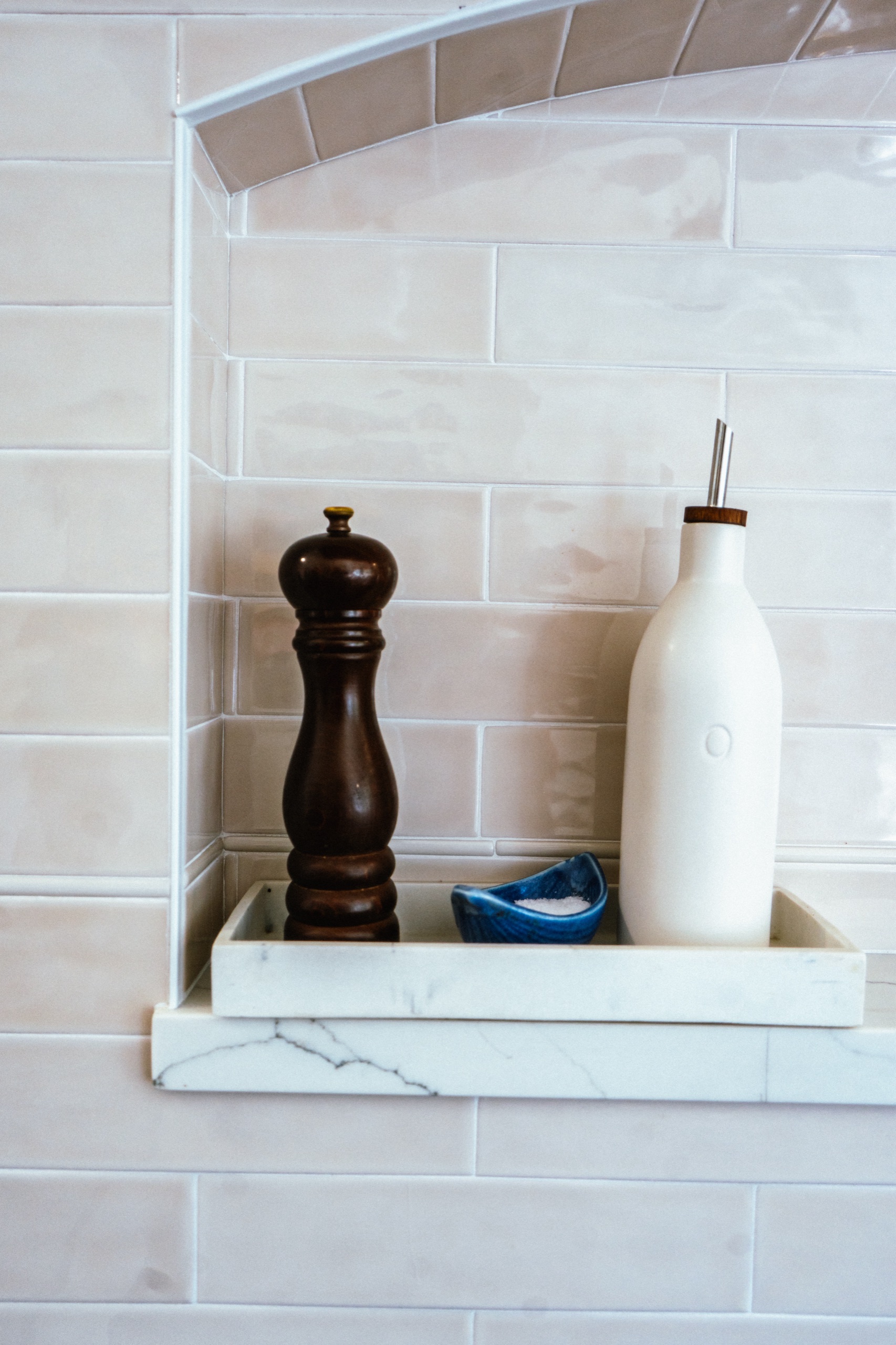 Marble niche shelf styled with a pepper mill, oil cruet and small blue dish